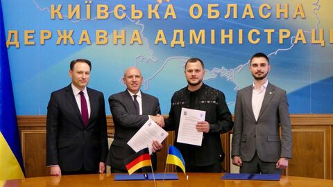 Rasch, Pentz, Kalashnyk und Geraschtschenko stehen nebenenander. Pentz und Kalashnyk reichen sich die Hand und halten Dokumente in den Händen.